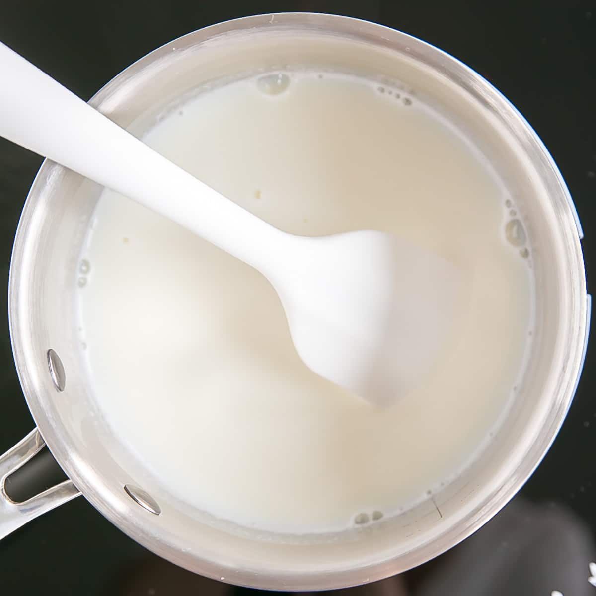This easy Pastry Cream (Creme Patissiere) recipe is simple and delicious. A rich and creamy vanilla custard you can use in a variety of decadent desserts. | livforcake.com Milk and vanilla in a pot on the stove.